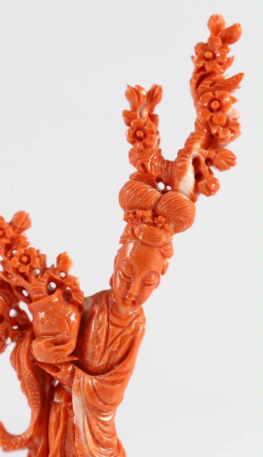 A Chinese carved coral figure of a flower fairy, 20th century, the carving 19cm high and 119g, wood stand